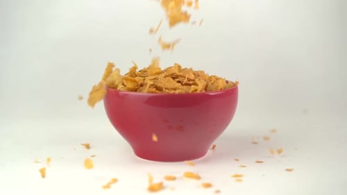 Cornflakes overflowing into cereal bowl in slow motion
