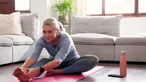 Senior Woman Stretching Legs on Yoga Mat at Home