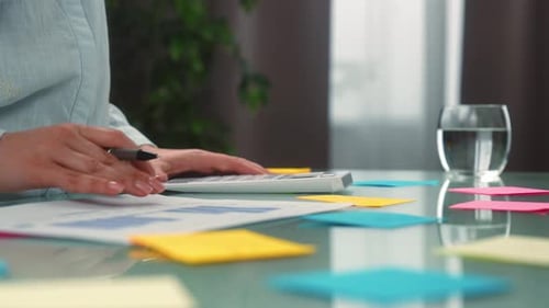 Pessoa analisando dados financeiros com calculadora e gráficos