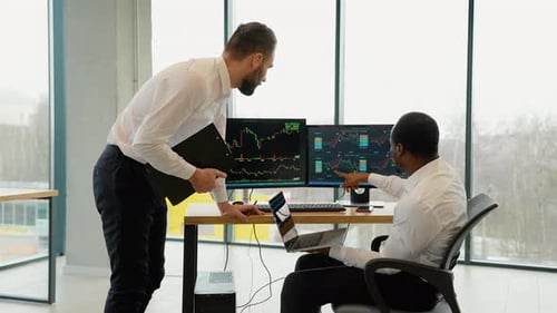 Deux négociants diversifiés, courtiers en vêtements de cérémonie, travaillent à l'aide d'ordinateurs au bureau