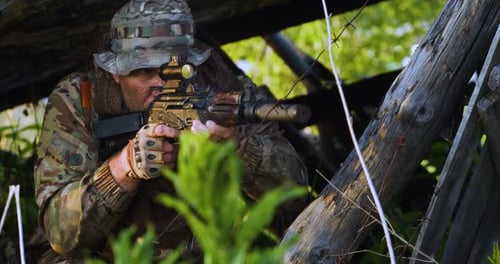 Man in Camouflage Aims Rifle in Nature