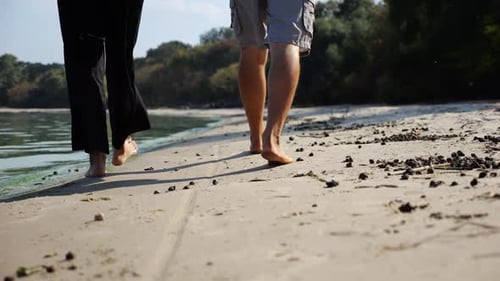 Bare Feet of Couple Stepping Together Along Sand Beach at Coastline Male and Female Legs of Pair