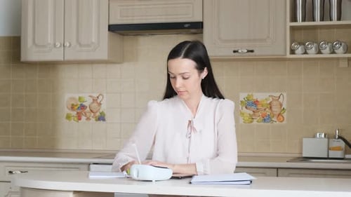 Woman Using Electronic Device, Writing in Notebook