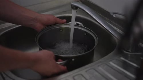 Cooking at Home Man Filling Water to a Pot Hand Using a Silver Faucet and Adding More Water to a