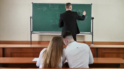 Instructor Writing Equations on Chalkboard, Students in Class