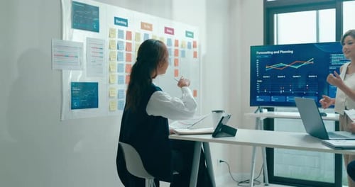 Group of Asian businesspeople work together leads business meeting uses presentation TV in office.