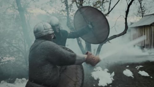 Two Medieval Warriors in Armour Attacking Knight with Two Swords in Burning Fort