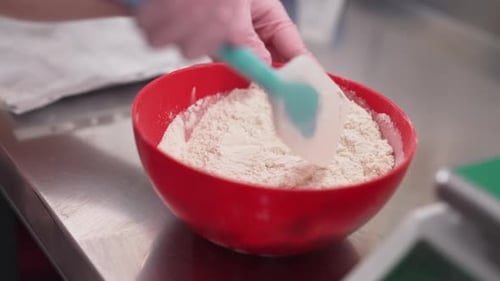 Hands Mixing White Flour in Red Bowl