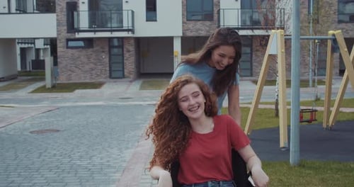 Laughing Friends Wheelchair Ride Through Modern Neighborhood