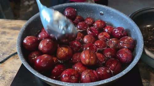 Cooking Juicy Plums in Syrup With Spoon