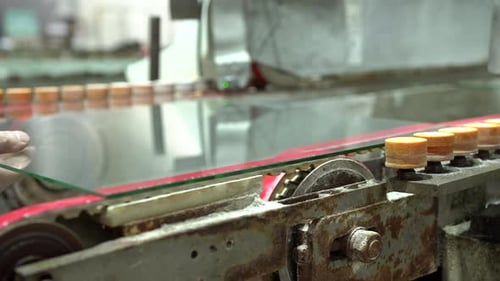 Industry machine for smoothing edges of glass panels in a factory. Rounded glass panel edges. A work