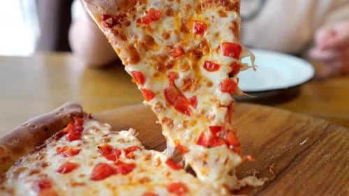 Woman Takes Bite of Pizza Slice with Look of Satisfaction