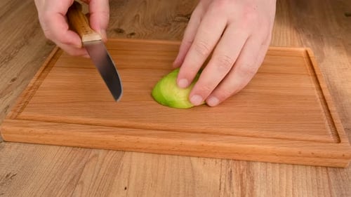 Slicing Avocado Half on Wooden Cutting Board