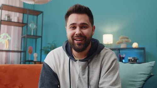 Bearded Man Waving and Talking Indoors on Couch