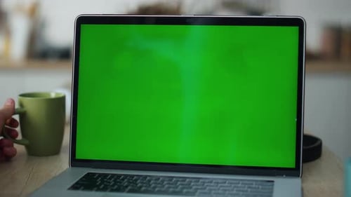Laptop with Green Screen and Coffee Mug on Desk