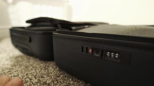 Close-up shot of traveler packing and closing carry-on luggage.