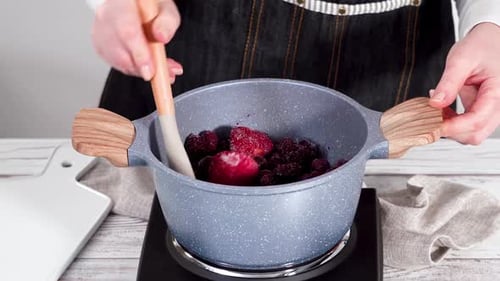 Woman Cooks Berries in Pot on Stove