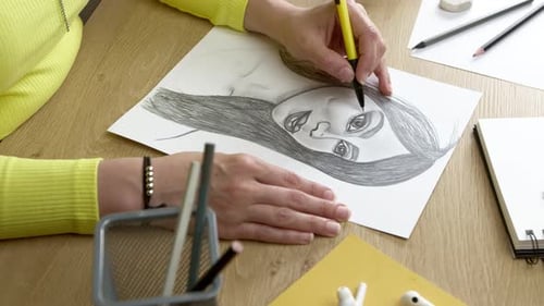 Der Künstler zeichnet ein Frauenporträt auf Papier.