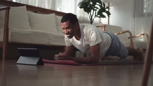Man doing plank looking at a tablet