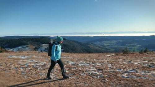 Woman walking along mountain range, enjoying picturesque mountains on background