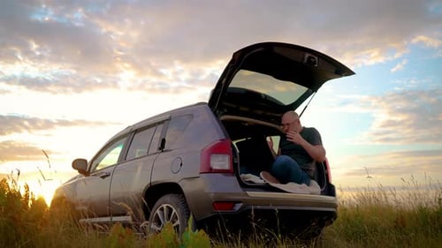 Homem irritado de óculos fala emocionalmente com companheiros, usa laptop, trabalha remotamente na natureza e