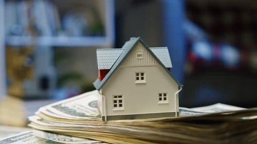 Rotating Model House Money Stacks Representing Cottage Real Estate Investment