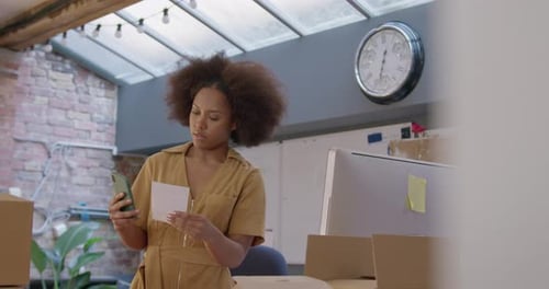 Woman Uses Smartphone near Boxes Indoors