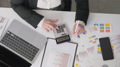 Un espace de travail professionnel comprenant une calculatrice pour ordinateur portable et divers documents financiers conçus pour