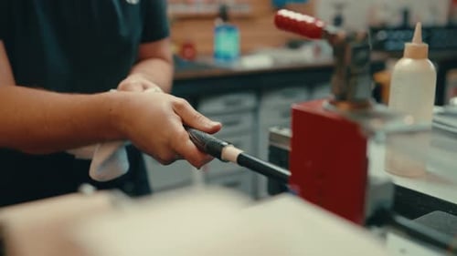 Vice grip holds down golf club shaft as caucasian male hands slide golf grip onto golf club shaft fo