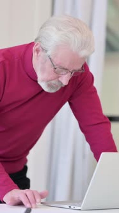 Senior Man Using Laptop Computer at Desk Indoors