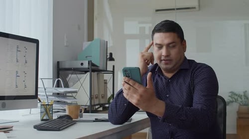 Adult Manager Checking Smartphone at Desk in Office