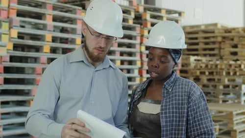 Engineer Explaining Plan of Work to Female Warehouse Worker