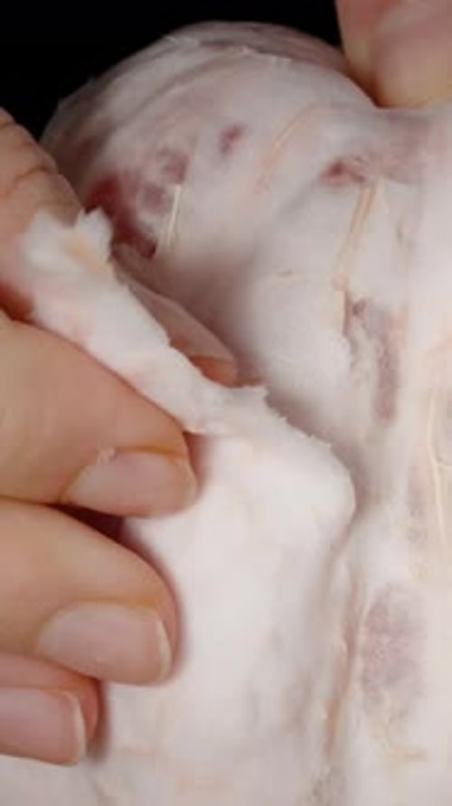 Vertical video. Close-up of female hands peeling the thick skin off the pomelo flesh.