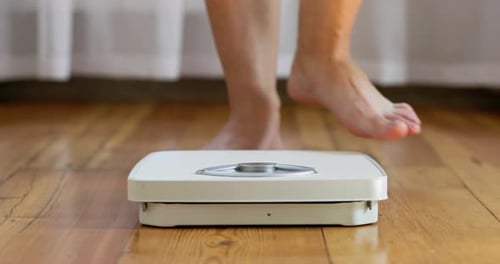 Woman Weighing Herself on Bathroom Scale