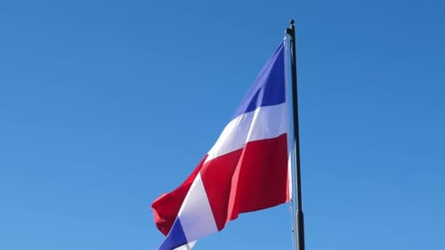 Flying and Waving Flag of Dominican Republic on Blue Sky Background