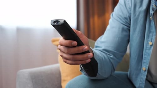 Man Spending Time at Home Switching Channels on TV with Remote Control