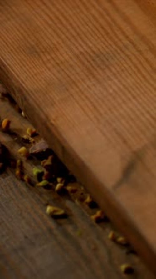 Crushed Pistachios Grinding on Wooden Surface – Vertical Rustic Food Shot