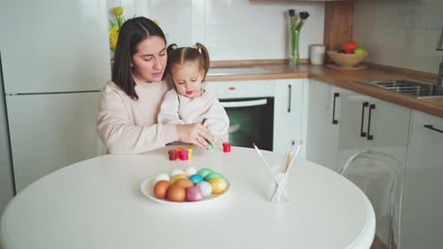 Happy Easter Holiday. Beautiful mother and daughter paint and decorate an egg