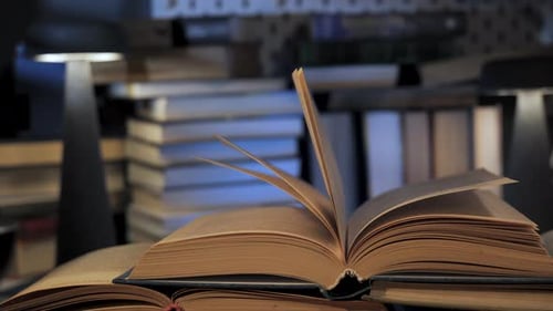 Old Books Piled with Lamp Light Flickering Pages