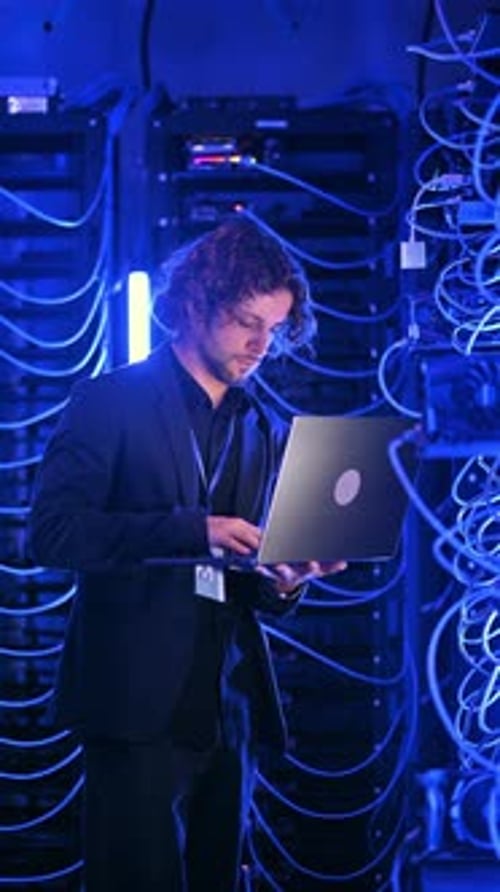 Man Working With Laptop in Dark Server Room