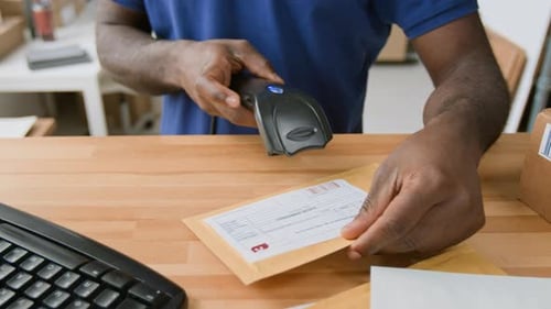 Worker scans mailing label with scanner at desk