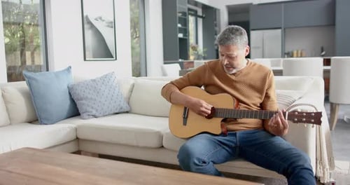 Man Plays Acoustic Guitar on Couch at Home