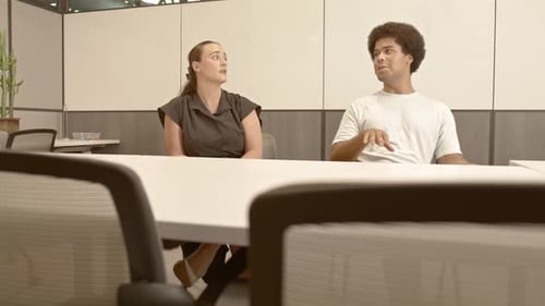 African American male in his 20's and a caucasian female in her 20's talking in business meeting wit