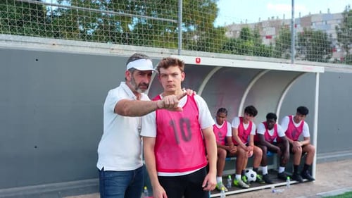 Soccer Coach Instructing Young Player on the Sidelines