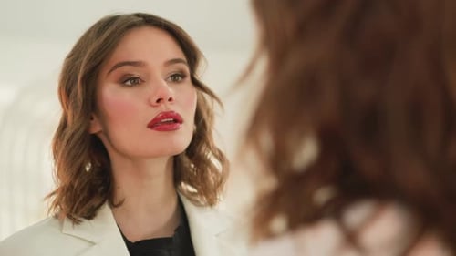 Glückliche Frau lächelt, wenn sie sich professionelles Make-up im Gesicht ansieht