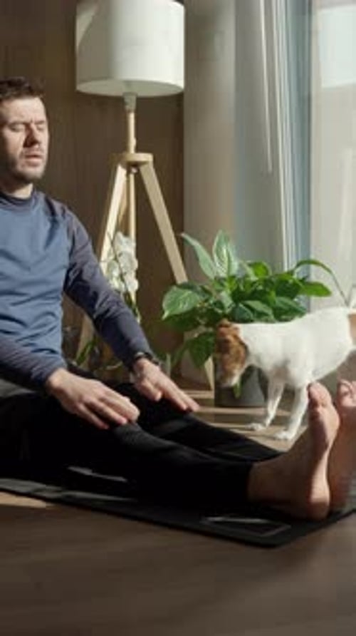 Man Stretching on Yoga Mat with Small Dog