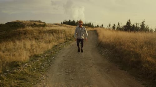 Redhead Man Jumps on Mountain Path at Sunset