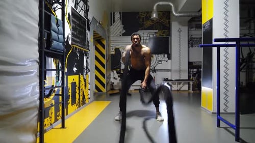 Strong African Athlete Training with Battle Ropes at Fitness Centre Muscular Afro American Sportsman