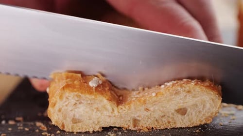 Koch schneidet Vollkornbrot in Nahaufnahme auf dem Holzschneidebrett