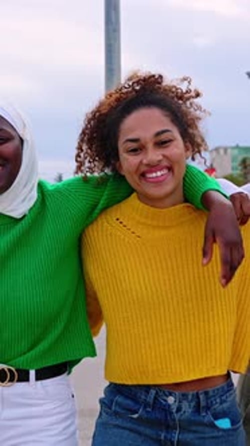 Vista frontal de mulheres jovens e diversas se abraçando caminhando juntas ao ar livre